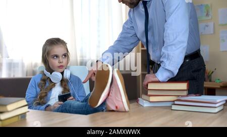 Papa schimpfte seine Tochter im Teenager-Alter, die Musik in Kopfhörern hört, in Konflikt Stockfoto