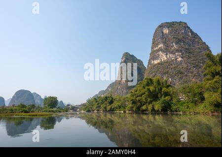 See mit Kalkkarsthügeln Nebellandschaft, die sich im Fluss in Yangshuo, Provinz Guangxi, China widerspiegelt Stockfoto