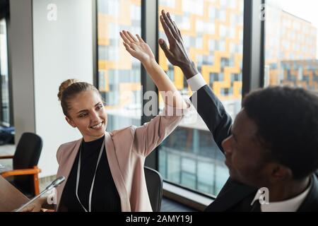 Happy business Paar ein hohes - fünf miteinander am Tisch sitzen während der Sitzung im Büro Stockfoto
