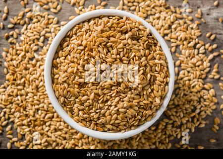 Golden Leinsamen in Weiß Schüssel auf Holztisch. Ansicht von oben Stockfoto