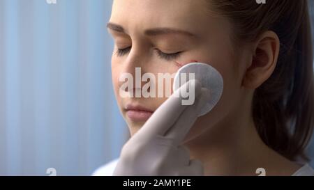 Arzt, der die Wunde auf dem Gesicht der Patientin nach einem Autounfall behandelt, erste Hilfe Stockfoto