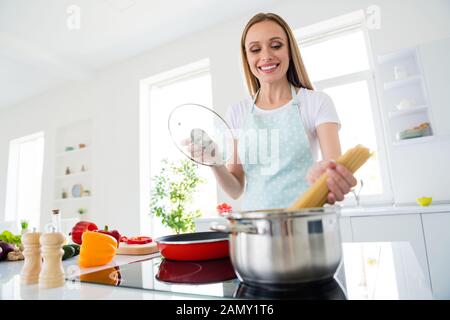 Foto von charmante Hausfrau genießen Wochenende Morgen kochen leckeres Abendessen holding Spaghetti das kochende Wasser stehen, weißes Licht Küche im Innenbereich Stockfoto