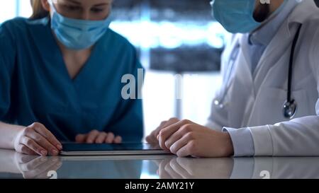 Labormitarbeiter, die die medizinischen Testergebnisse auf dem Laptop überprüfen und über Krankheit sprechen Stockfoto