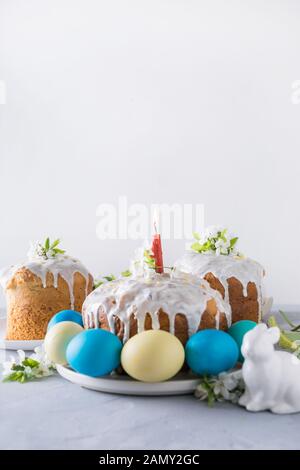 Osterkuchen und bunte traditionelle Eier, Frühlingsblumen in Vase. Nahaufnahme. Vertikales Format. Stockfoto
