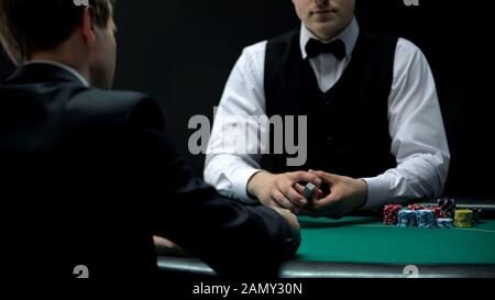 Erfahrener Croupier, der das Kartendeck bereit hält, um zu handeln, die Chance, im Poker zu gewinnen Stockfoto