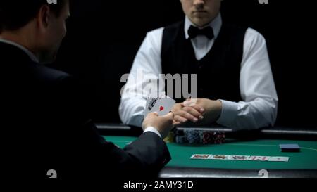 Glücklicher Casino-Kunde, der gute Karten in Kombination mit Poker sucht, starke Hand Stockfoto