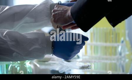 Wissenschaftler mit Handschellen für illegale Forschung, heimliche Pharmazielabors Stockfoto