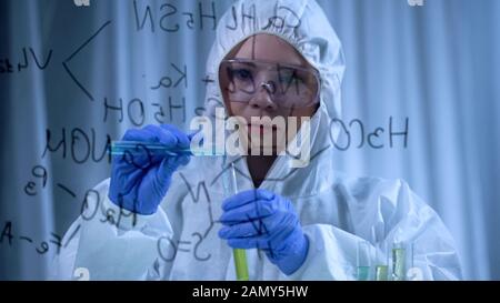 Weibliche Chemikerin mischt Flüssigkeiten, erforscht in der Kosmetologie, Formel im Vordergrund Stockfoto