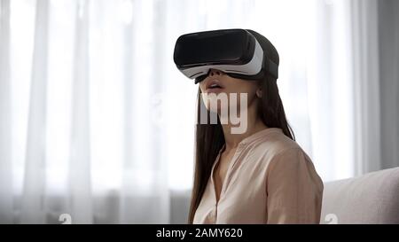 Staunende Frau, die zum ersten Mal ein VR-Headset verwendet, überwältigt von positiven Emotionen Stockfoto