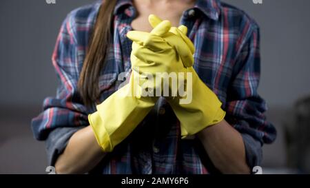 Festgestellte Frau in gelben Handschuhen, die bereit ist, den Haushalt zu reinigen, Ordnung und Sauberkeit Stockfoto