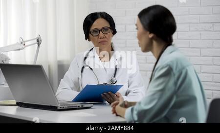 Patient bei Arztberatung, Therapeut hören und Symptome aufzeichnen Stockfoto