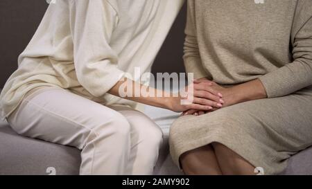 Tochter kuschelt sanft zu Mutter, die ihre fürsorglichen Hände streichelt, Familienbeziehungen Stockfoto