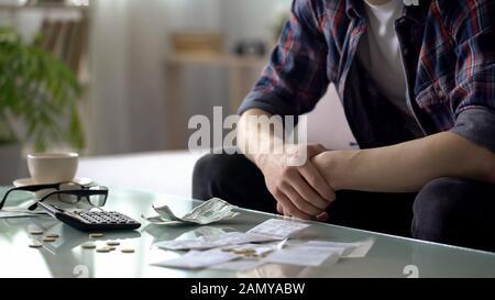 Junger Mann, der Hausfinanzierung rechnet, nur wenige Dollar und Cent für das nächste Gehalt übrig Stockfoto