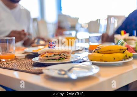 Gesundes Frühstück Konzept. Club Sandwich mit Englischer Flagge auf der Oberseite zusammen mit Obst und Saft zum Frühstück. Stockfoto