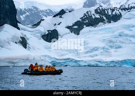 Touristen auf einem Schlauchboot Walbeobachtung in der Nähe eines Eisbergs. Fotografiert in Paradise Bay, Antarktis. Stockfoto