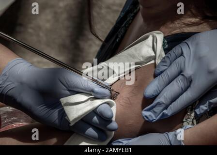 Bangkok, Thailand - 25 Aug 2019: Tätowieren Konzepte im Thai Stil. Tattoo Künstler erstellen eine Tätowierung auf dem Arm ist ein Mädchen mit einem spitzen aus Metall. Stockfoto