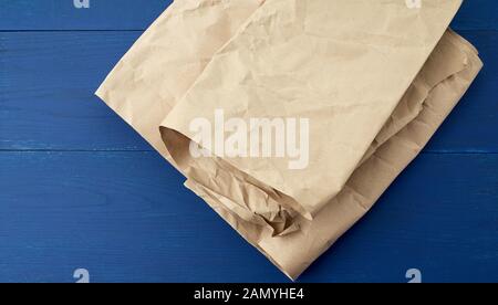 Gefaltetes braunes zerknittertes Blatt aus Kraftpapier auf blauem Holzhintergrund, Nahaufnahme Stockfoto