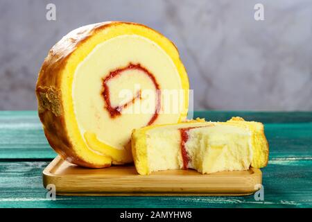 Golden süße Brötchen mit einem Stück zur Hälfte auf dem grünen Tisch gegessen Stockfoto