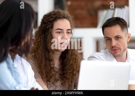 Verschiedene Arbeitsgruppen diskutieren über Arbeitsprojekt mit Laptop Stockfoto