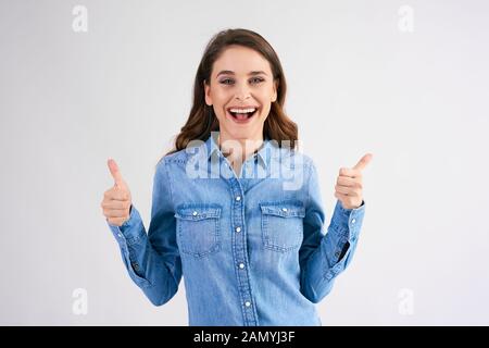 Porträt einer aufgeregten Frau mit Daumen nach oben im Studio Stockfoto