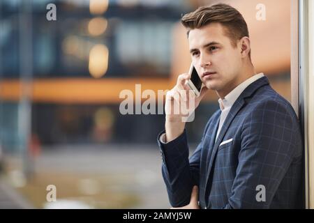 Junge schwere Geschäftsmann stand draußen und hat ein ernstes Gespräch am Handy Stockfoto