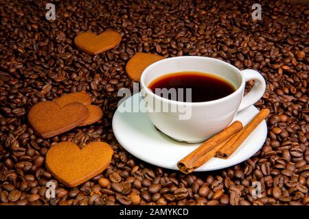 White Coffee Mug, Zimtstangen und Herzförmigen Lebkuchen Cookies auf der Kaffeebohnen background-image Stockfoto