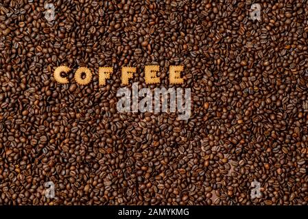 Das Wort Kaffee von Keks Buchstaben auf einem dunklen Kaffeebohne Hintergrund-Bild Stockfoto