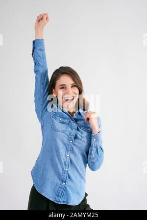 Erfolgreiche junge Frau mit erhobenen Händen Stockfoto