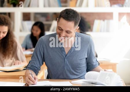 Lächelnder Student, der in der Bibliothek studiert und sich auf den Test vorbereitet Stockfoto