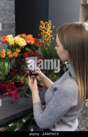 Frau, die Bilder von Blumen von Ihrem Smartphone. Das Mädchen Fotos die Blumen, die ihr Liebhaber ihr gab. Ein blumengeschäft ist Fotografieren ein Blumenstrauß tha Stockfoto