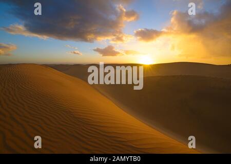 Sonnenuntergang in der Wüste, Sonne, Sonne, blauer Himmel und schöne Wolken. Goldenen Sanddünen in der Wüste in Maspalomas, Gran Canaria, Kanarische Inseln, Spanien Stockfoto