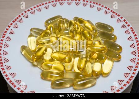 Gold Omega 3 Fischöl kapseln in einer Platte. Kapsel gold Öl gel ergänzen. Omega 3 Fischöl, Gesundheitswesen Apotheke medizinische Konzept. Stockfoto