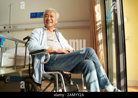 Asiatischer alter Mann sitzt im Rollstuhl im Pflegeheim oder in der Krankenstation und sieht glücklich und zufrieden aus Stockfoto