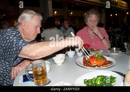 Touristen essen und trinken Chili Crab und Bier, East Coast Parkway, Singapur Stockfoto