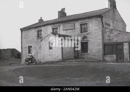 1965, historisches Bild aus dieser Zeit, ein Motorrad außerhalb der Tan Hill Inn, eine einzigartige historische Pub aus dem 17. Jahrhundert hohe Stand-up in den Yorkshire Dales, England, UK geparkt. In einer Höhe von 1732 m über dem Meeresspiegel ist es die höchste Pub in Großbritannien und steht direkt auf der Pennine Way, in Großbritannien die erste Entfernung Fußweg, Alfred Wainwright begonnen und 1965 eröffnet. Stockfoto