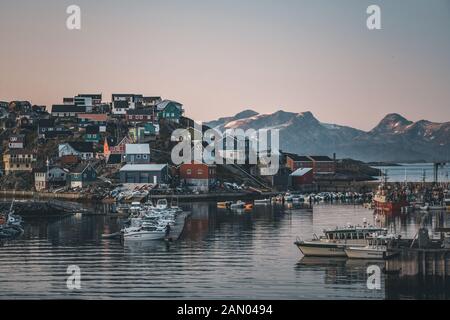 Blick auf den Sonnenuntergang über Maniitsoq arktische Stadt in Grönland. Berge im Hintergrund während der Mitternachtssonne. Farbenfrohe Häuser und Panorama. Ansicht zum Anschluss mit Stockfoto