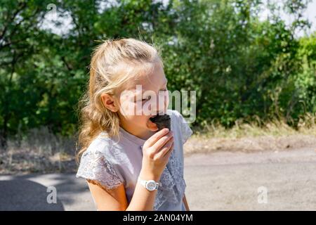 Schwarzes Eis in eine Tasse in den Händen eines Mädchens. Stockfoto