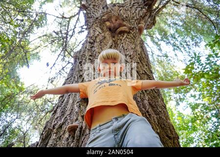 Ein Junge in der Nähe eines großen Baumes, Weitwinkel Foto, Ansicht von unten. Stockfoto