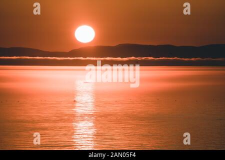 Schöner Sonnenuntergang mit Bergen und Eisbergen. Arktischer Kreis und Ozean. Sonnenaufgangshorizont mit rosafarbenem Himmel bei Mitternachtssonne. Stockfoto