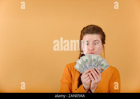 Ein überrascht und Crazy Girl befasst sich mit dem Geld, das Sie in Ihren Händen hält. Stockfoto