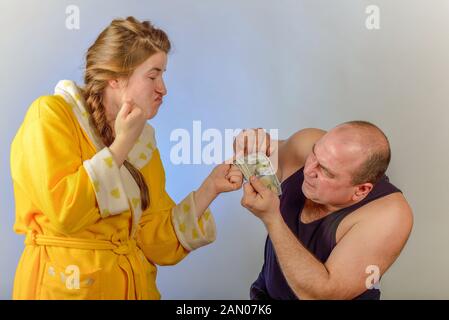 Eine Frau schlägt ihr Mann und nimmt Geld von ihm, das Konzept der sozialen Probleme in den Familien. Stockfoto