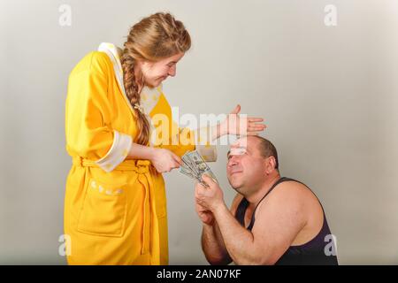 Eine Frau schlägt ihr Mann und nimmt Geld von ihm, das Konzept der sozialen Probleme in den Familien. Stockfoto