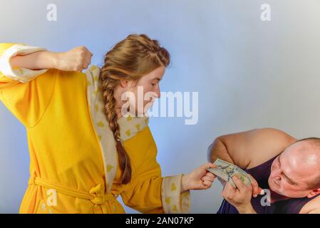 Eine Frau schlägt ihr Mann und nimmt Geld von ihm, das Konzept der sozialen Probleme in den Familien. Stockfoto