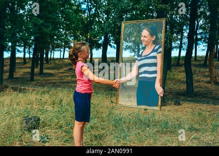 Mystische Frau Gespenst aus dem Spiegel, ruft ein kleines Mädchen in ihre geheimnisvolle Welt. Stockfoto
