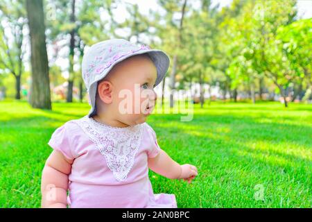 Kleines Mädchen sitzen auf grünem Gras, ganz nah. Stockfoto