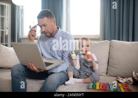 Ein Vater auf der Suche ernsthafte, die von zu Hause aus arbeiten Stockfoto