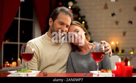 Zärtliche Liebespaar umarmt, Weihnachtsdekorationen funkelnd, fröhliches Familienporträt Stockfoto