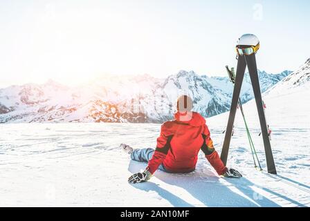 Skifahrer Athlet in den Alpes Berge sitzen an einem sonnigen Tag - erwachsenen Mann genießen den Sonnenuntergang mit Wolken Gang neben ihm - Wintersport und Ferienhäuser Konzept Stockfoto