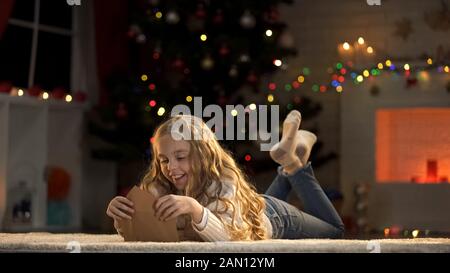 Adorable Mädchen, die Umschlag mit Brief an den Weihnachtsmann vorbereiten, glauben an Weihnachtszauber Stockfoto