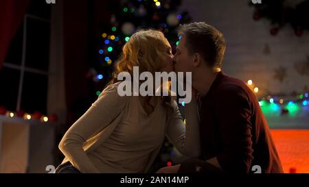 Paar küsst sich leidenschaftlich unter Weihnachtsbaum, Ferien-Atmosphäre, Liebe Stockfoto